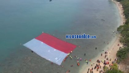 Peserta membentangkan Bendera Merah Putih di perairan Pulau Merak Besar, Kota Cilegon, usai mengikuti aksi transplantasi terumbu karang dan pelepasan tukik dalam rangka peringatan HUT RI ke-81.
